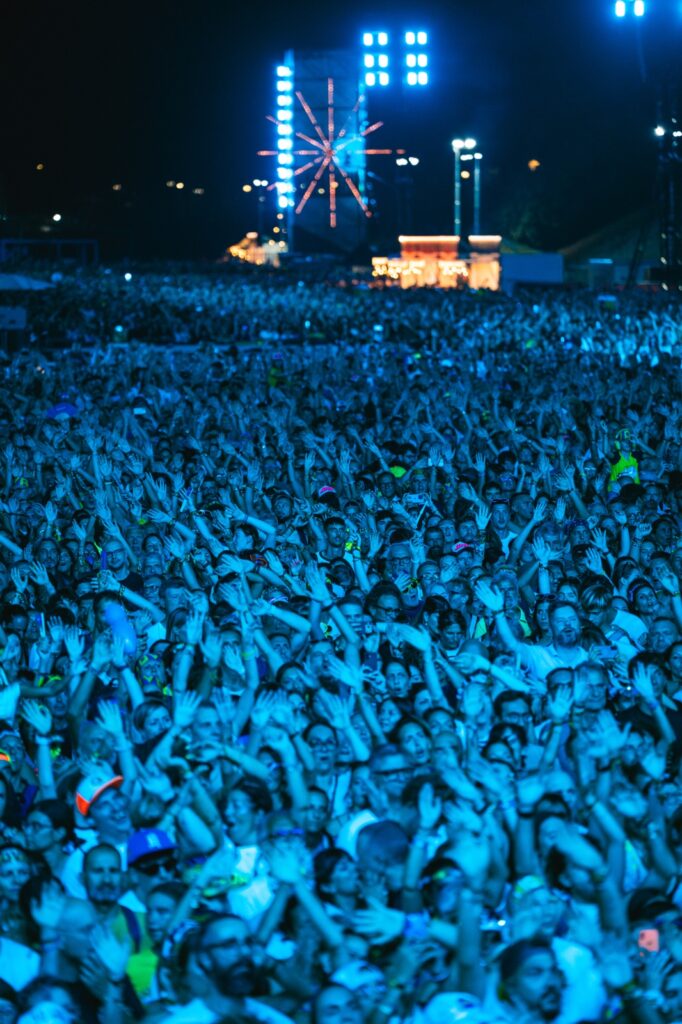 Folla in visibilio al Jova Summer Party immersa in un'illuminazione blu.